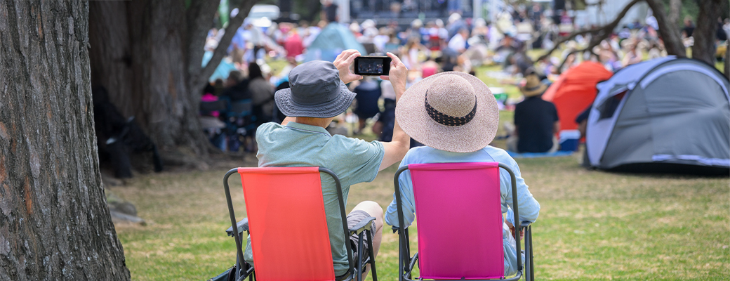 Image of man and woman from the behind sitting in lawn chairs at an outdoor festival